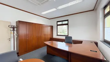 Geräumiges Büro mit Teppichboden, Holzschränken und einem großen Schreibtisch, ausgestattet mit Klimaanlage.