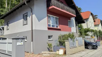 Das Haus präsentiert sich mit einer zweifarbigen Fassade und einem Balkon im Obergeschoss.