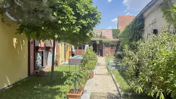 Gepflegter Gartenbereich mit kleinem Pool, umgeben von Grünflächen und Gebäuden.