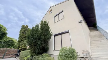 Außenansicht eines modernen Gebäudes mit markanter Architektur, Außentreppe und gepflegter Gartenanlage.