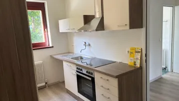 Funktionale Einbauküche mit hellen Fronten, Holzarbeitsplatte und Fenster mit Blick ins Grüne.