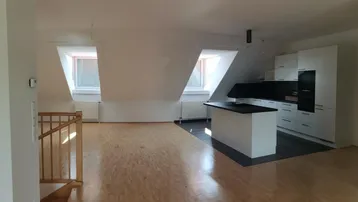 Heller Wohnbereich mit integrierter Küche, Dachschrägen und Parkettboden, ideal für offenes Wohnen.