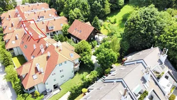 Luftaufnahme einer Wohnanlage mit roten Ziegeldächern, umgeben von üppigem Grün und Bäumen.