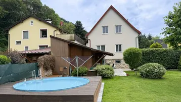 Großer Garten mit Rasenfläche, kleinem Pool auf Holzdeck und Blick auf die umliegenden Hügel.