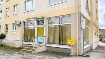 Außenansicht eines modernen Geschäftsgebäudes mit großen Schaufenstern und Klimaanlage.
