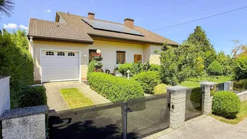 Einfamilienhaus mit gepflegtem Vorgarten, Garage und Solaranlage auf dem Dach.