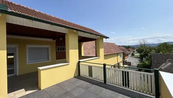 Geräumige, geflieste Terrasse mit Geländer und Blick auf die umliegende Landschaft.