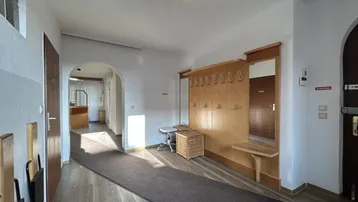 Geräumiger Flur mit Garderobe, Holzvertäfelung und Laminatboden, der zu weiteren Räumen führt.