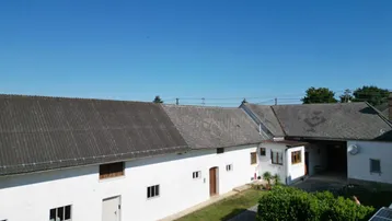 Hinteransicht des Anwesens mit mehreren Gebäuden, einem Gartenbereich und Solarpaneelen.