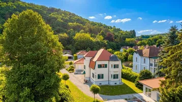 Luftaufnahme eines eleganten Hauses mit großem Garten, Whirlpool und umgebender grüner Hügellandschaft.