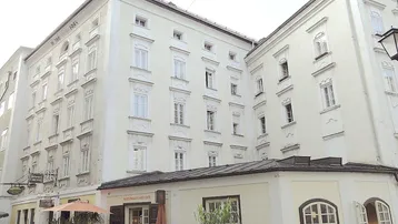 Traditionelles Gebäude mit mehreren Stockwerken und einem Café im Erdgeschoss in einer städtischen Umgebung.