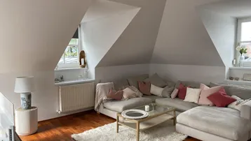 Gemütliches Wohnzimmer mit großem Ecksofa, Holzboden und schrägen Dachfenstern.