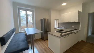 Moderne Küche mit integrierter Essecke, Kücheninsel und hellem Laminatboden.