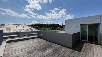 Große Holzterrasse mit weitem Blick über die Stadt und die umliegende grüne Landschaft unter blauem Himmel.