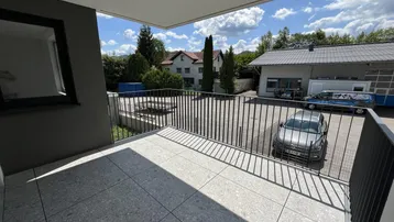 Geräumiger Balkon mit Fliesenboden und Blick auf die Umgebung und grüne Hügel.