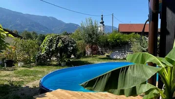 Gartenbereich mit ovalem Aufstellpool, Holzdeck und malerischem Bergblick im Hintergrund.