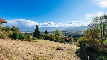 Weitläufiges Grundstück mit Panoramablick auf die umliegende Landschaft und Berge unter blauem Himmel.