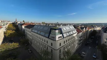 Luftaufnahme eines historischen Gebäudes mit modernem Dachausbau und weitem Stadtblick.