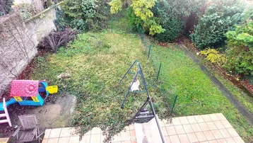 Grüner Gartenbereich mit Spielgeräten und Terrasse, ideal für Familien.