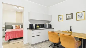 Kleine Küchenzeile mit Esstisch und Blick in ein angrenzendes Schlafzimmer.