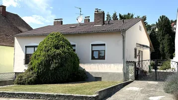 Einfamilienhaus mit Vorgarten, Zufahrt und Satteldach in ländlicher Umgebung.