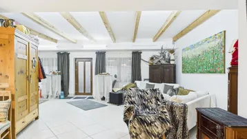Helles Wohnzimmer mit Holzbalken an der Decke, Kaminofen und gemütlicher Einrichtung.