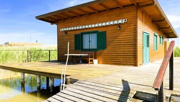 Holzhaus auf Stelzen über dem Wasser mit einer Holzterrasse und Blick auf die umliegende Natur.