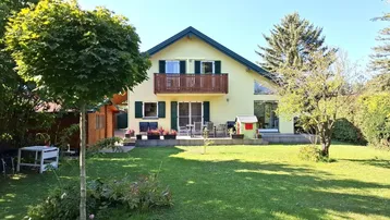 Großzügiger Gartenbereich mit Rasenfläche, Bäumen und einer Terrasse vor dem Haus.