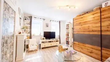 Helles Wohnzimmer mit hellem Holzboden, TV-Möbeln und einem großen Holzschrank.