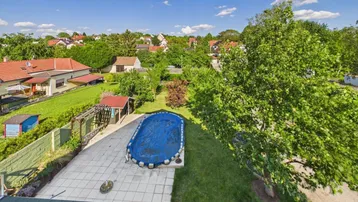 Luftaufnahme des Gartens mit einem Pool, Rasenflächen und umliegenden Häusern in der Nachbarschaft.