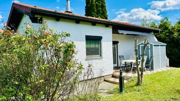Helles Haus mit weißer Fassade, Terrasse und Garten in ländlicher Umgebung.