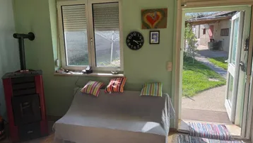 Gemütliches Wohnzimmer mit Kaminofen, Sofa und Zugang zum Garten, hell und einladend.