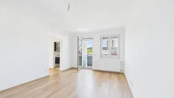 Helles Wohnzimmer mit Parkettboden, weißen Wänden und Zugang zu einem Balkon.