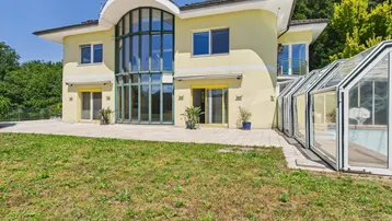 Großzügige Villa mit weitläufigem Garten, Terrasse und einem überdachten Poolbereich.