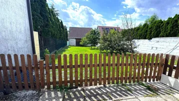 Grüner Gartenbereich mit Holzzaun und Rasenfläche, ideal für Entspannung im Freien.