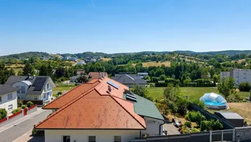 Luftaufnahme eines Hauses mit Ziegeldach, Solaranlage und weitem Blick über die Landschaft.