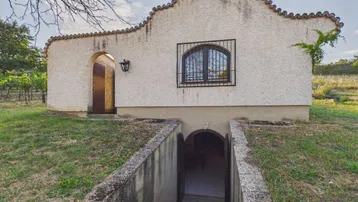 Kleines Gebäude mit traditionellem Ziegeldach und einem Eingang, der zu einem Keller führt.