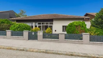 Einfamilienhaus mit gepflegtem Vorgarten und Zaun, von der Straße aus gesehen.