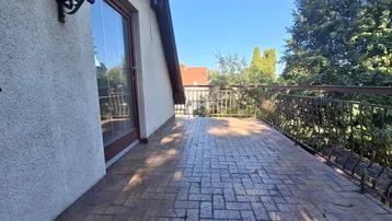 Geräumige Terrasse mit gemustertem Pflaster und schmiedeeisernem Geländer, ideal für Entspannung im Freien.