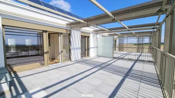 Große Dachterrasse mit Fliesenboden, Pergola-Struktur und weitem Blick über die Landschaft.