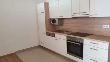Moderne Einbauküche mit weißen Schränken, Holzarbeitsplatte und integrierten Geräten.