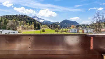 Panoramablick vom Balkon über grüne Wiesen und Wälder bis zu den majestätischen Bergen.