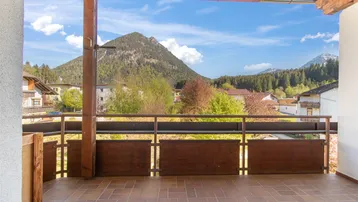 Geräumiger Balkon mit Fliesenboden und weitem Blick auf die umliegende Berglandschaft.