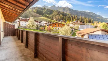 Großer Holzbalkon mit Bergblick und grüner Umgebung.