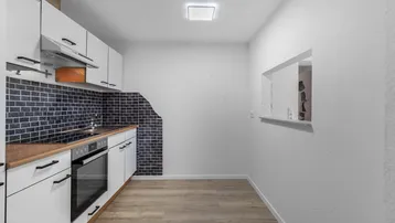 Moderne Küche mit weißen Schränken, Holztheke und dunklem Fliesen-Spritzschutz.