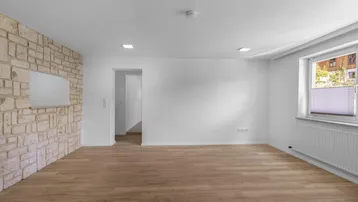 Helles Zimmer mit Laminatboden und einer dekorativen Natursteinwand, ideal als Wohnbereich.