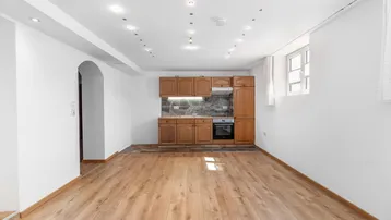 Heller Raum mit Laminatboden, integrierter Küchenzeile und Einbaustrahlern an der Decke.