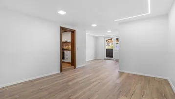 Heller, leerer Raum mit modernem Laminatboden und Zugang zu einer Küche.