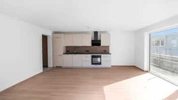 Helle, moderne Küchenzeile in einem offenen Wohnbereich mit Holzboden und Zugang zur Terrasse.