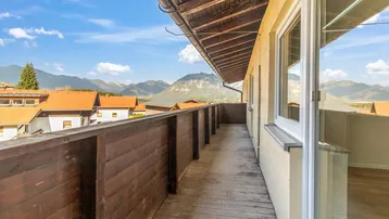 Langer Holzbalkon mit weitem Blick auf die umliegende Berglandschaft.